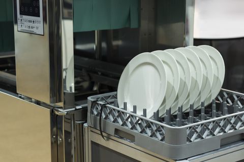 Grey plastic dishrack with 6 dishes emerging from a commercial dishwasher