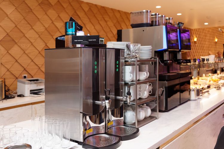 Row of commercial coffee machines in a line atop a white countertop in a retail environment