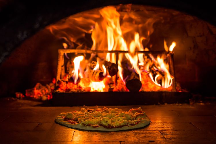 Wood fired Masonry pizza oven showing flames and pizza being heated