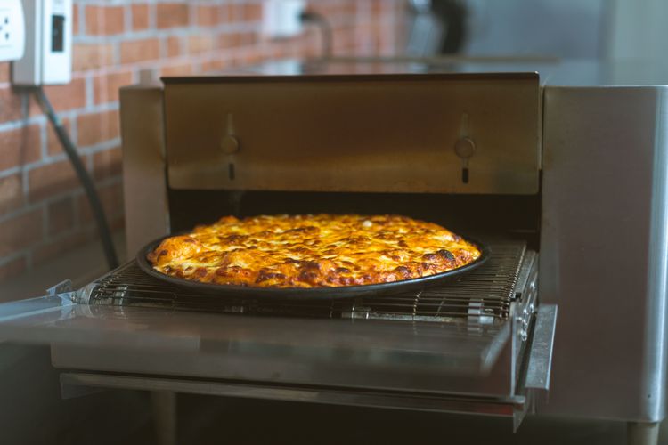 Golden Brown with melty cheese pizza emerging from conveyor oven
