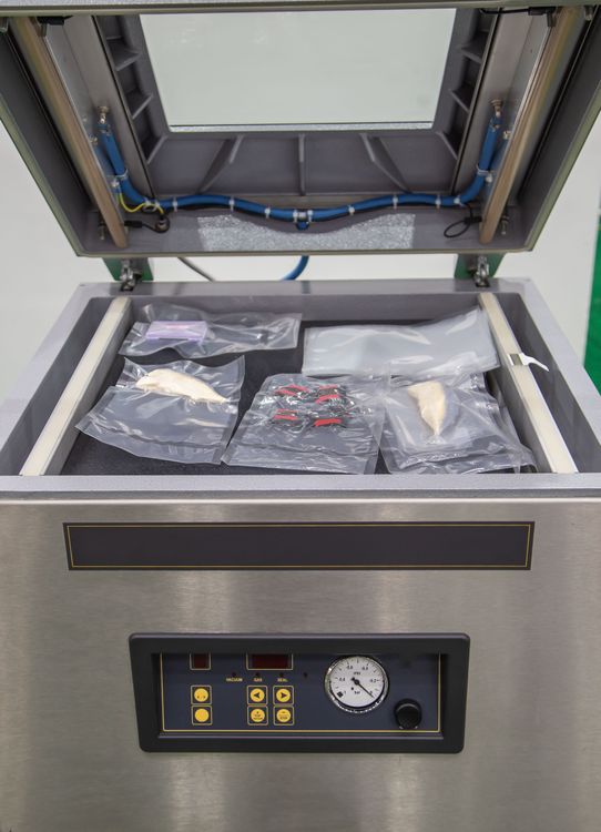 Cabinet Style Vacuum Sealer with the lid open and bagged food inside the chamber