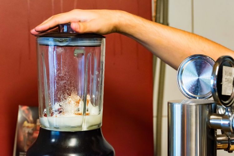 Barista holding down lid of glass jarred blender